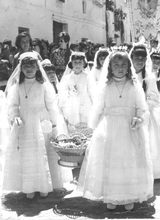 Niñas de Primera Comunión portando cestas con pétalos de flores antes del paso de la Custodia en la procesión del Corpus de Membrilla (Ciudad Real). Años 60. Fondo Los Legados de la Tierra. Archivo de la Imagen de Castilla-La Mancha.