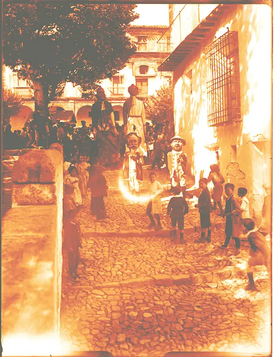 Fiesta de gigantes y cabezudos bajando por delante de la Iglesia de la Trinidad durante la celebración de las fiestas del Corpus de Alcaraz (Albacete). 1907. Fotografía de Pedro Román. Fondo Rodríguez. AHP Toledo.