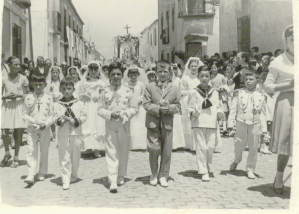 Grupo de niños vestidos de Primera Comunión preceden el paso de la Custodia en el Corpus de Bolaños de Calatrava (Ciudad Real). Años 60. Fondo Los Legados de la Tierra. Archivo de la Imagen de Castilla-La Mancha.