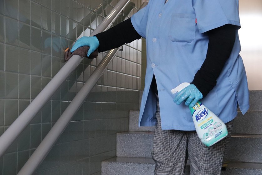 Personal de limpieza desinfectando la barandilla de un colegio
