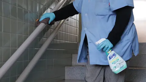 Personal de limpieza desinfectando la barandilla de un colegio